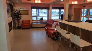 A modern reception area with a counter, seating, and large windows.