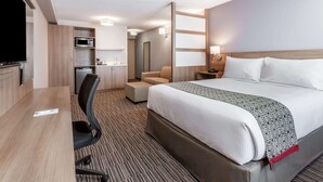 A hotel room with a bed, a desk, a chair, a microwave, a small kitchenette, and a TV. - Microtel by Wyndham Casselman (Casselman)
