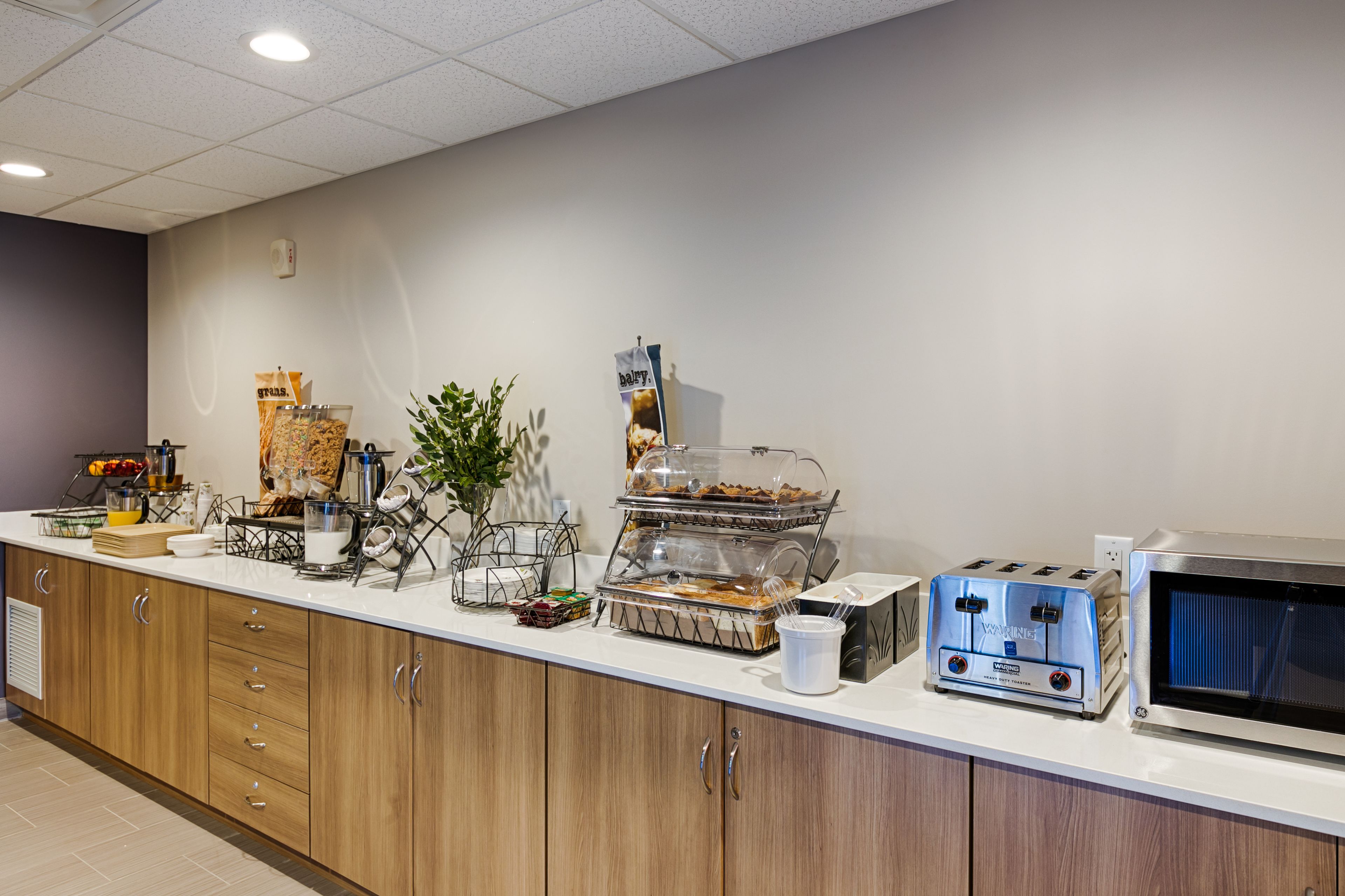 A breakfast bar with a toaster, microwave, and various food items.