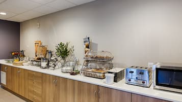 A breakfast bar with a toaster, microwave, and various food items.