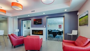 A modern interior with red leather sofas, a fireplace, and a dining area. - Microtel by Wyndham Casselman (Casselman)
