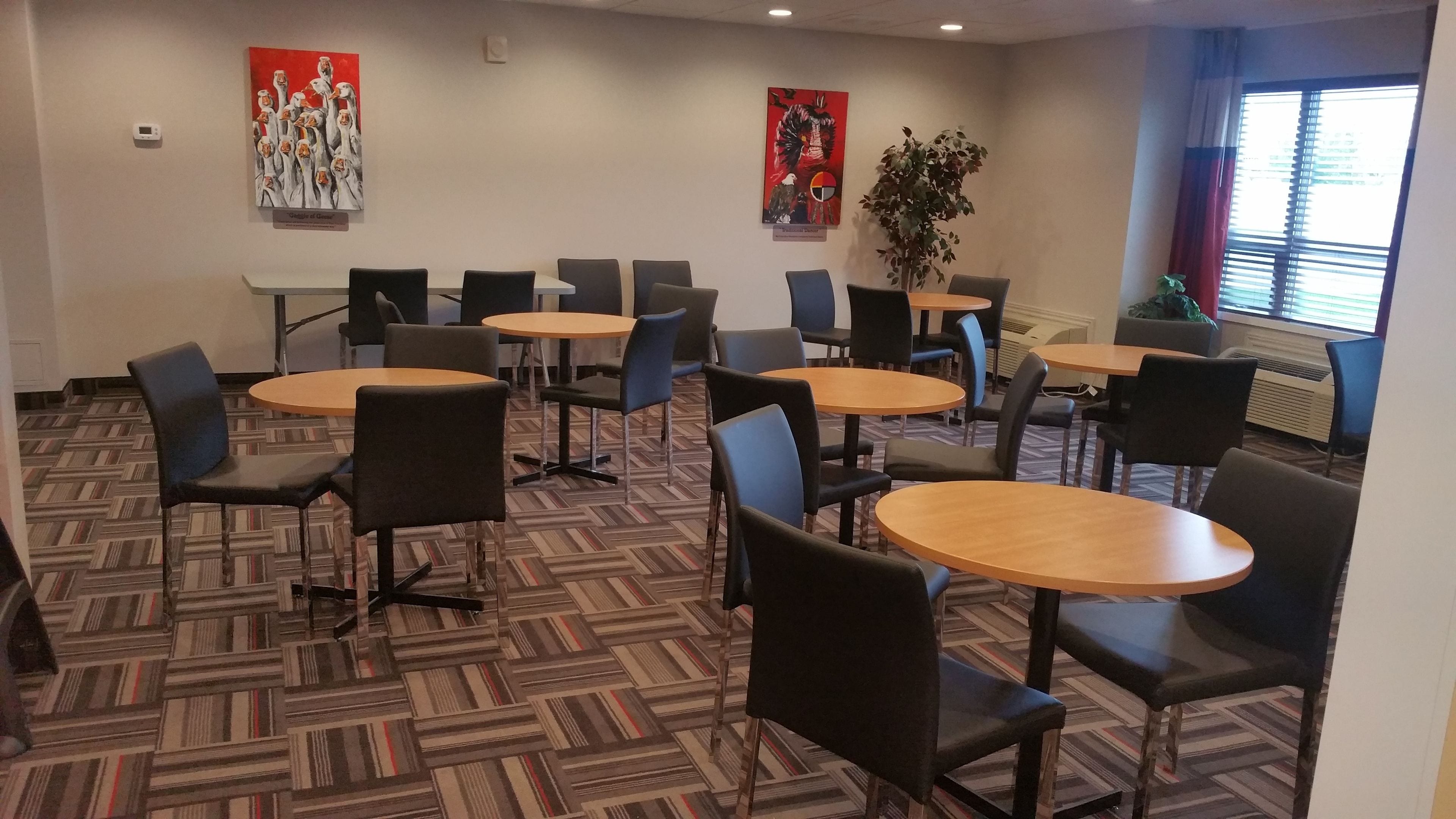 A conference room with round tables and chairs, a patterned carpet, and two artworks on the walls.