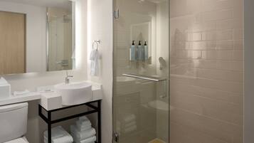 A modern bathroom with a glass-enclosed shower, a white sink, and a black shelf with towels.