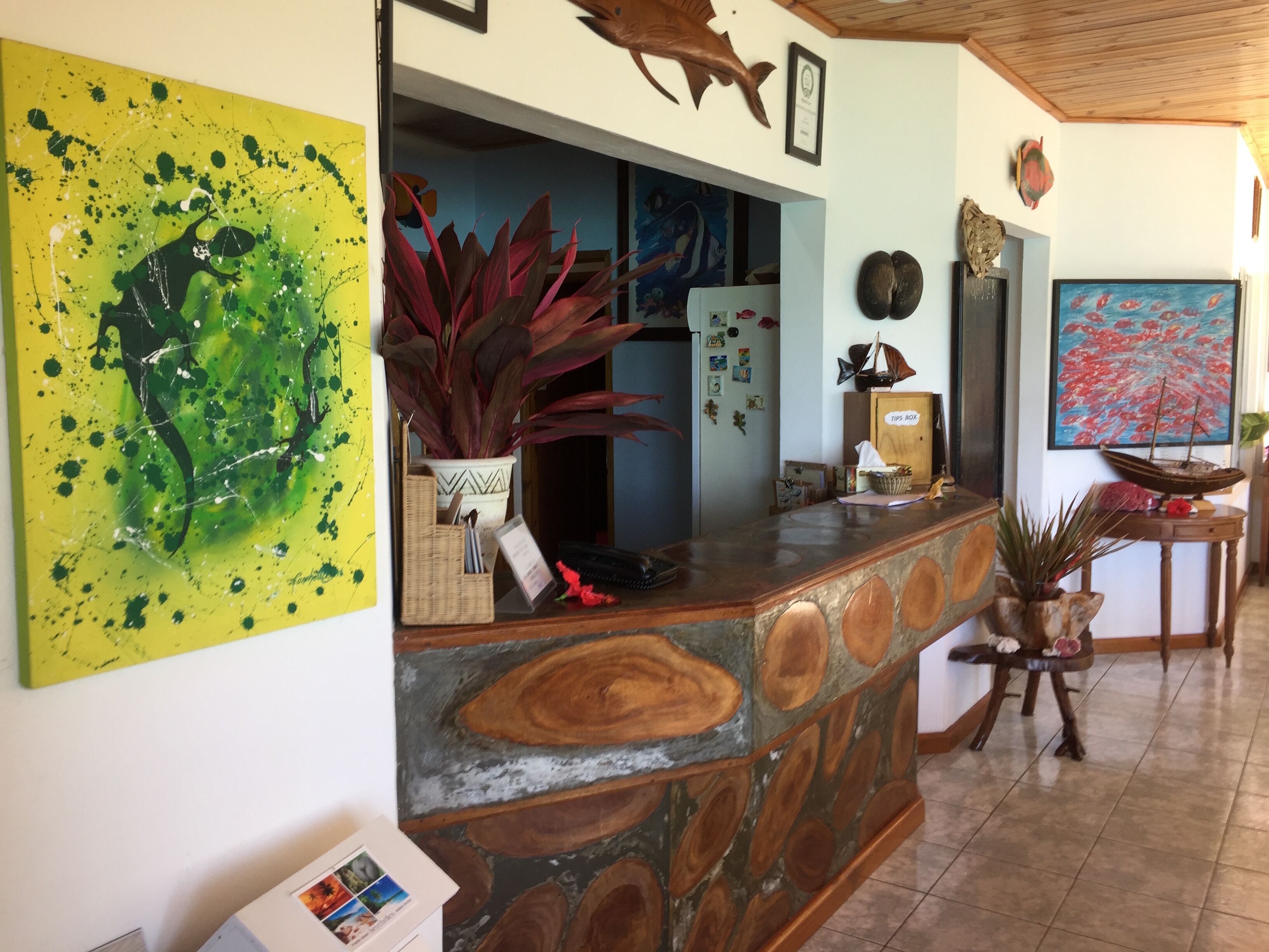 Un área de recepción con mostrador de piedra, un cuadro abstracto de gran tamaño y varios elementos decorativos.