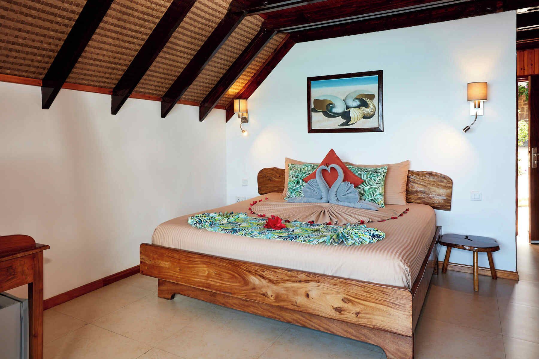 Un dormitorio con una cama de madera, un cuadro en la pared y dos lámparas adosadas.