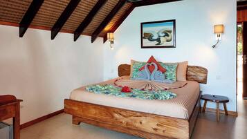 Un dormitorio con una cama de madera, un cuadro en la pared y dos lámparas adosadas.