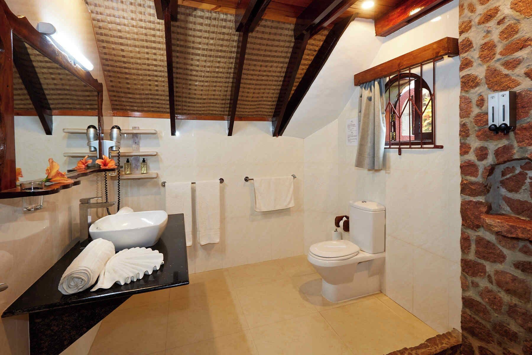 A bathroom with a black countertop sink, white toilet, and a shower area.