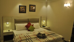 Ein Hotelzimmer mit einem großen Bett, zwei Nachttischen, einer Stehlampe und zwei Wandleuchten.