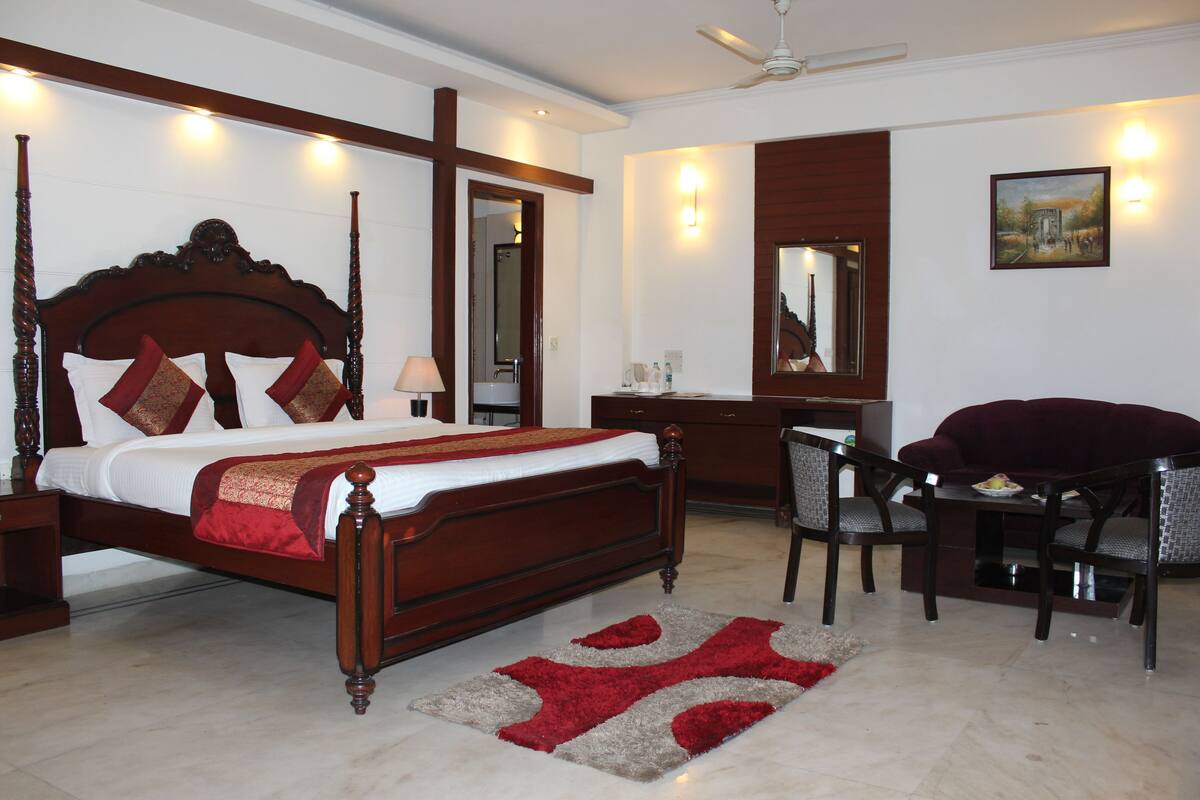 A bedroom with a wooden four-poster bed, a desk with a chair, and a large mirror.