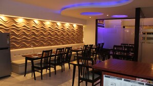 Ein Restaurant mit wellenförmigem Wanddesign, Holztischen und -stühlen sowie einem Menüständer.