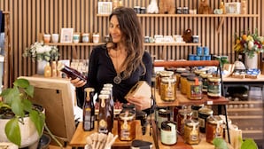 A woman in a store with shelves of jars and bottles, wooden furniture, and a striped wall. - BIG4 Launceston Holiday Park (South Launceston)