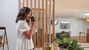 A woman in a white dress holding a jar, standing in a room with wooden slats, a plant, and various jars on a table. - BIG4 Launceston Holiday Park (South Launceston)