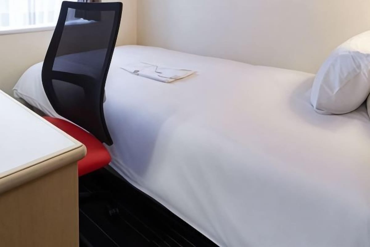 A hotel room with a bed, a desk, and a chair.