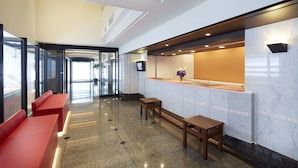 Una hall moderna con una reception, area salotto e ingresso in vetro.