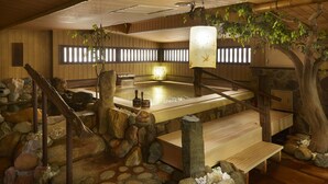 Una tradizionale onsen giapponese con interni in legno, ambientazioni in pietra e una panca di legno.