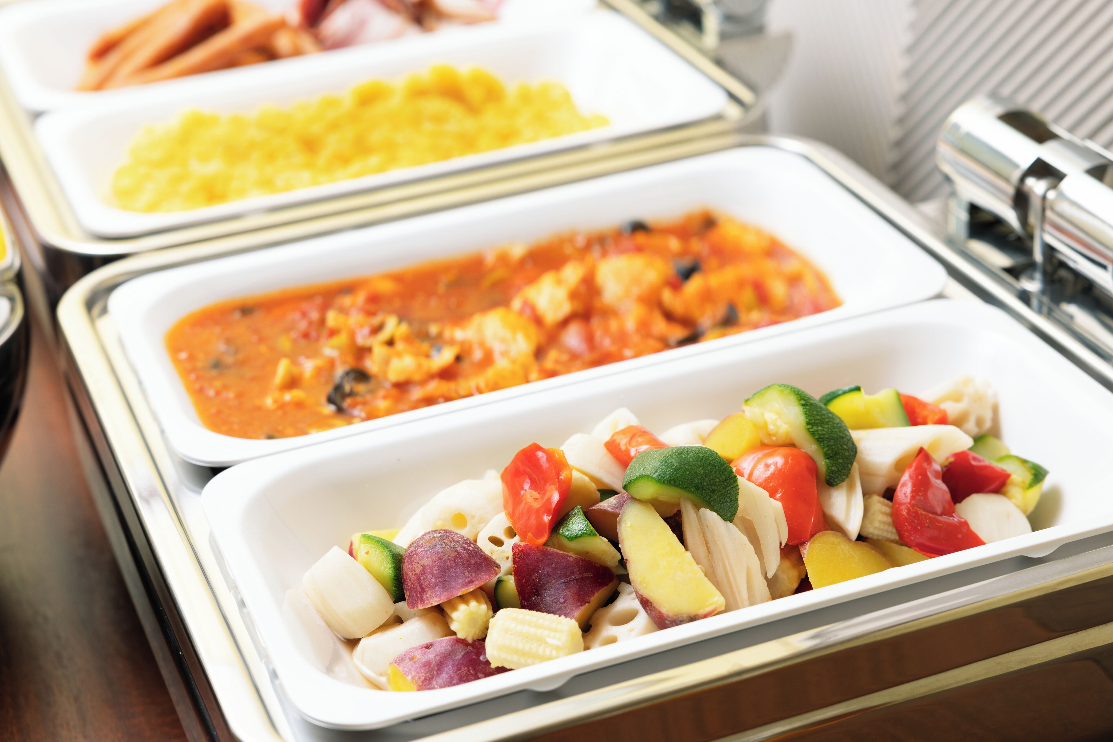 A buffet with various dishes including pasta, a tomato-based dish, and a vegetable salad.