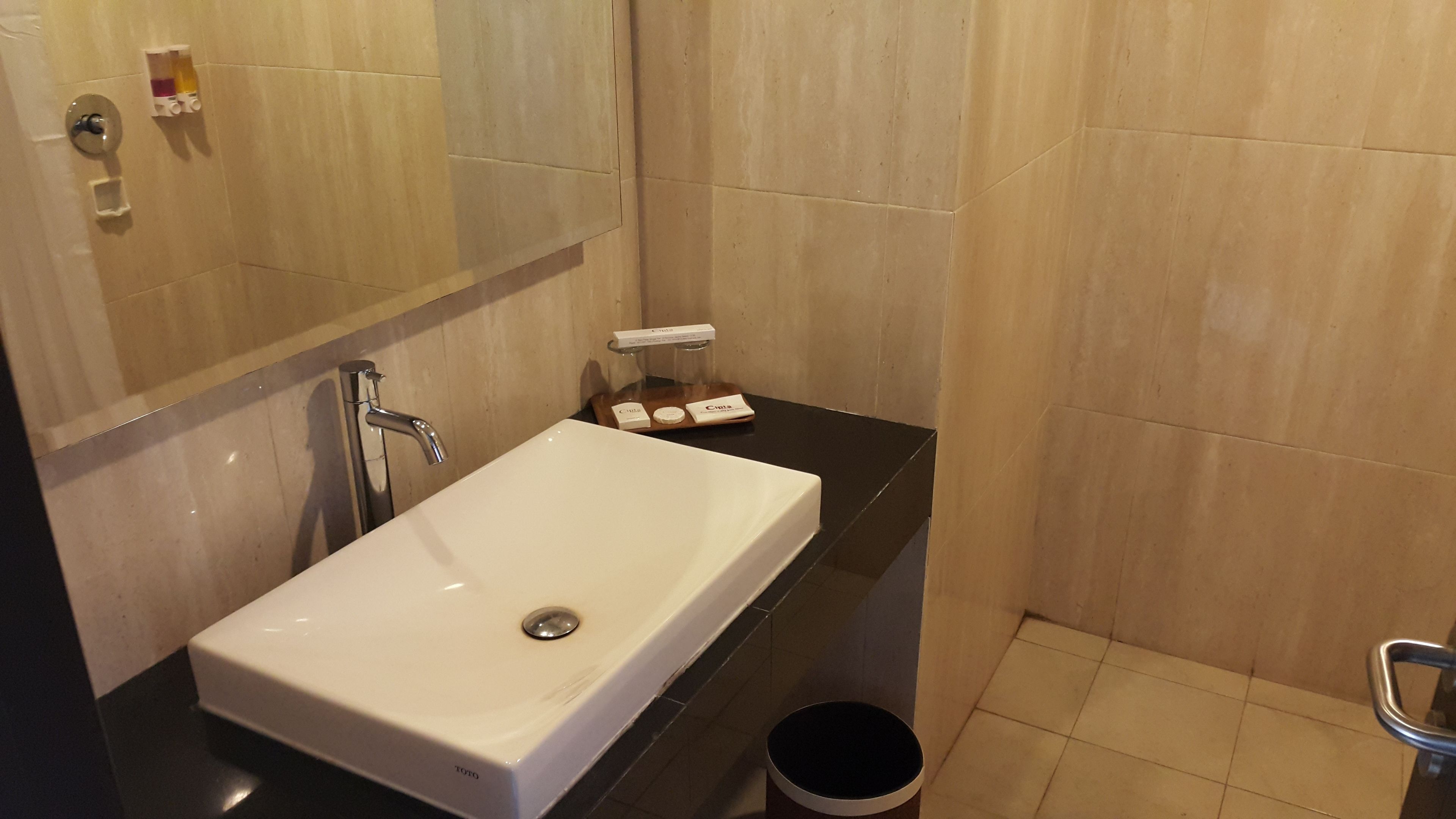 Une salle de bain avec un lavabo blanc, un miroir et un plan de toilette noir.
