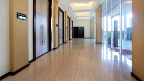 A hotel corridor with a sign reading "Krishna 1", doors, and a glass wall with a view outside. - Cipta Hotel Pancoran (Jakarta)