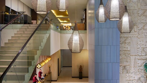 A modern lobby with a staircase, hanging pendant lights, and a decorative wall. - Cipta Hotel Pancoran (Jakarta)