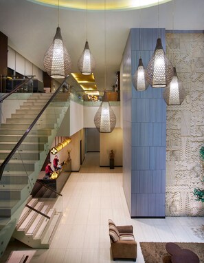 A modern lobby with a staircase, hanging pendant lights, and a decorative wall. - Cipta Hotel Pancoran (Jakarta)