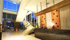 A modern lobby with a marble reception desk, a staircase, and large windows. - Cipta Hotel Pancoran (Jakarta)