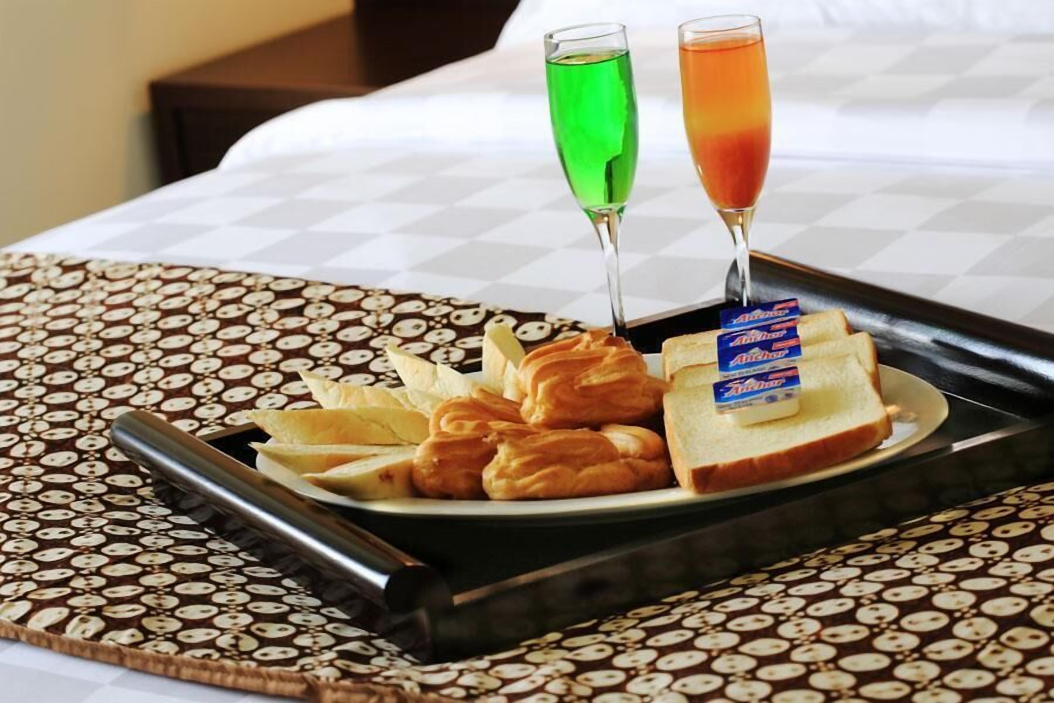 Un plateau avec des croissants, une tranche de pain beurrée et deux verres de boissons, le tout posé sur une nappe à motifs.