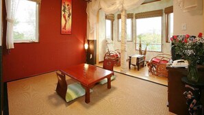 A room with a wooden table and chairs, a red accent wall, and a painting. - Scotch Court (Nasu)