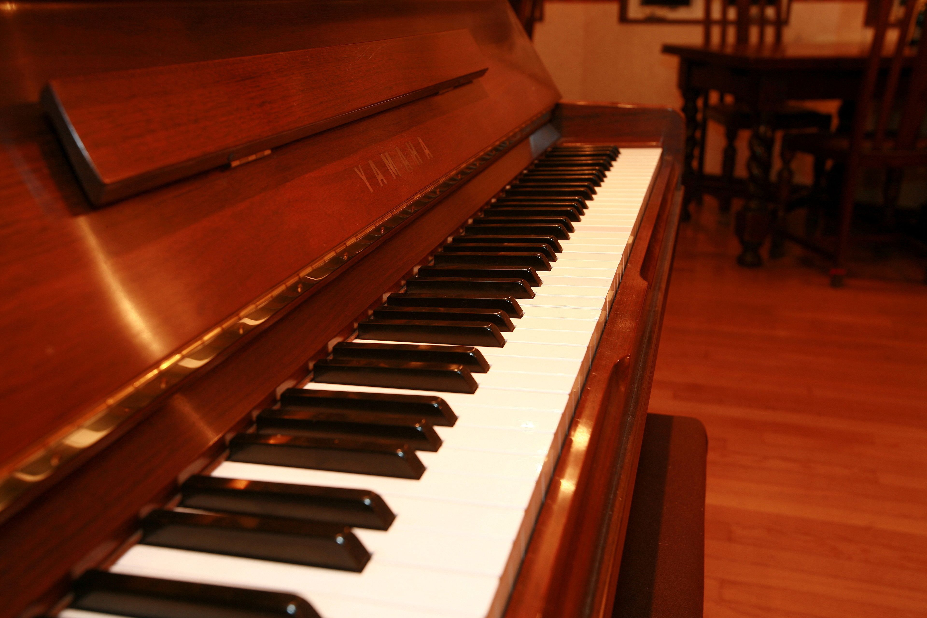Un piano vertical Yamaha con terminación de madera y teclas blancas y negras.