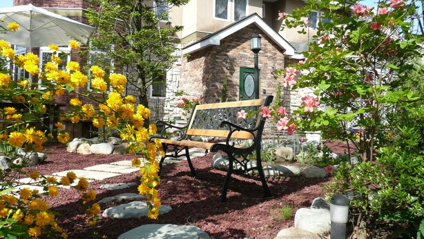 A garden with a bench, rocks, and flowering plants. - Scotch Court (Nasu)