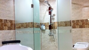 Une salle de bain avec une douche à parois de verre, une baignoire blanche et des toilettes.