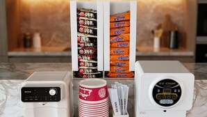 Une cuisine équipée de deux machines à café, d’une pile d’assiettes rouges et blanches, et d’un présentoir à serviettes.