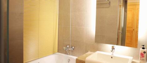 A modern bathroom with a bathtub, a shower, and a sink.