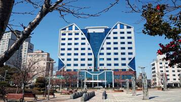 A modern building with a unique architectural design, featuring a central glass facade and a symmetrical layout.