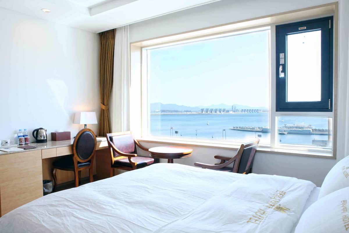 Ein Hotelzimmer mit Bett, Schreibtisch, Stühlen und Meerblick, sowie ein Fenster mit Brückenblick.