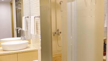 Un baño moderno con cabina de ducha de vidrio, lavamanos blanco y espejo.