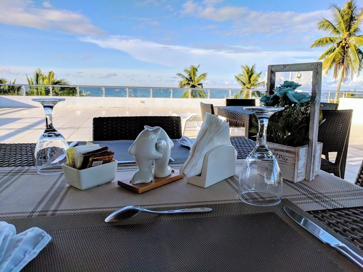 Ein Tisch für zwei Personen mit Blick auf den Ozean und Palmen im Hintergrund.
