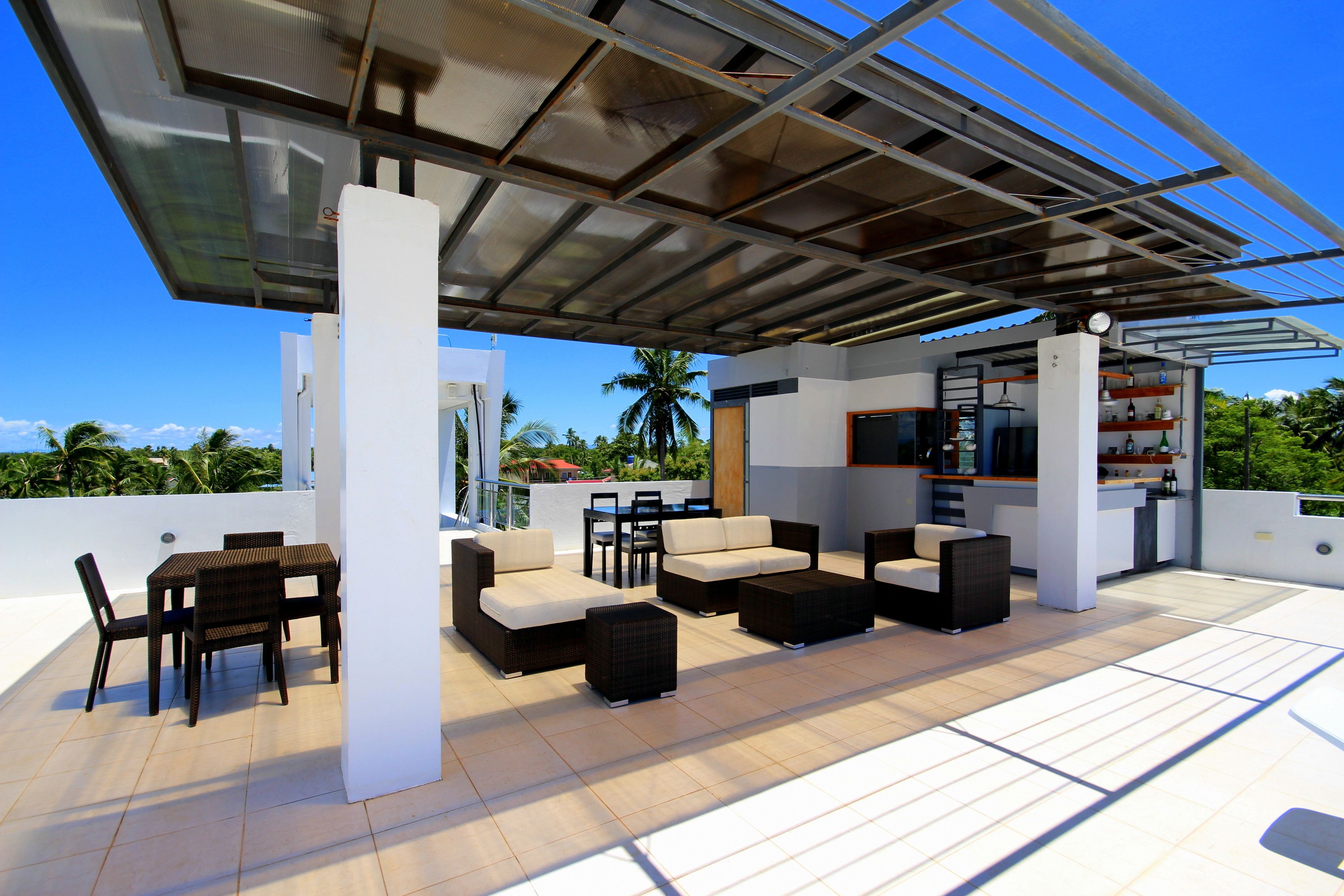 An outdoor patio with a dining area, sofas, and a bar area.