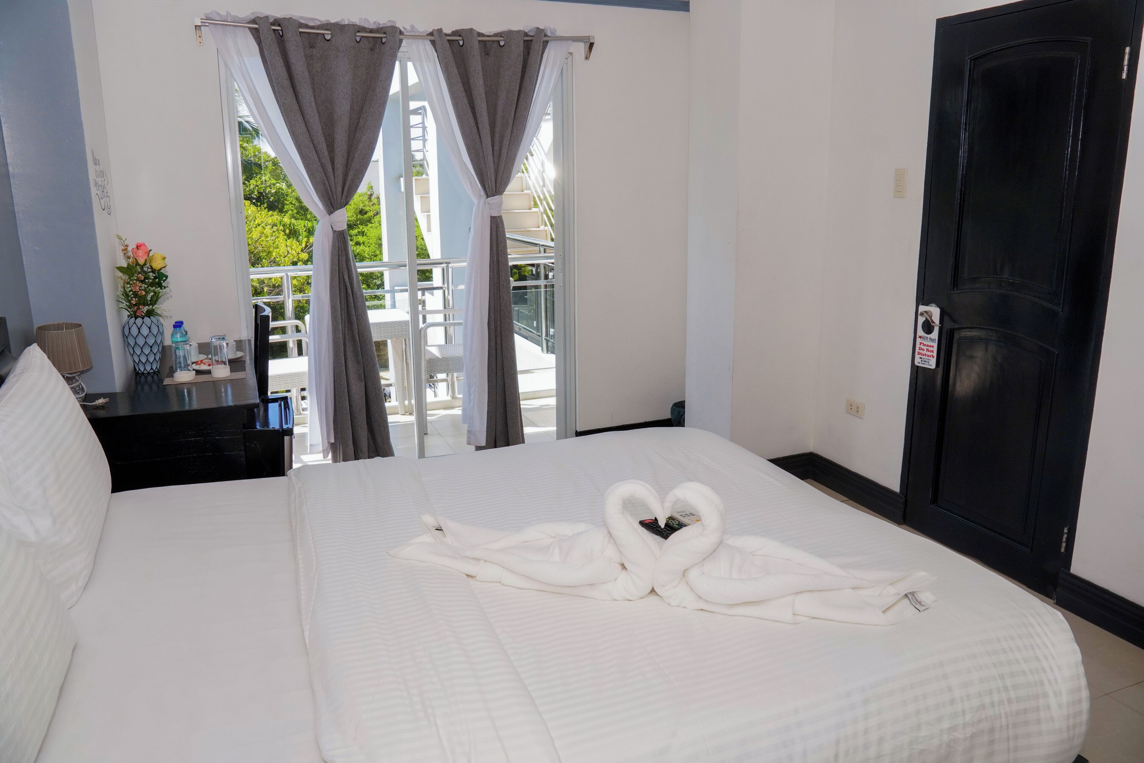 A hotel room with a bed, a desk, a TV, and a view of the outside.