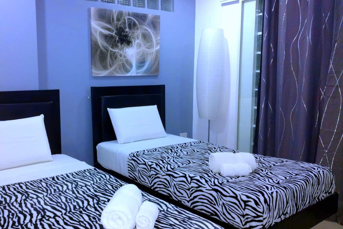 Dos camas individuales con ropa de cama estilo cebra, almohadas blancas y toallas enrolladas.