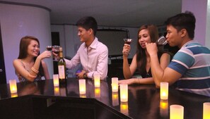 A group of people seated around a table with candles, holding wine glasses.