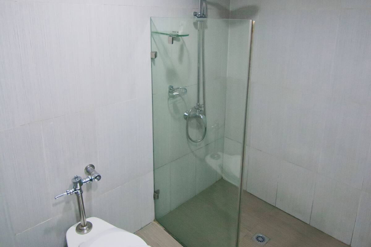 A bathroom with a glass-enclosed shower, a toilet, and a sink.