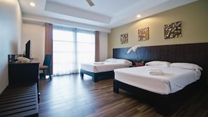 Une chambre d’hôtel avec deux lits, un bureau avec un téléphone, une chaise et un ventilateur de plafond.