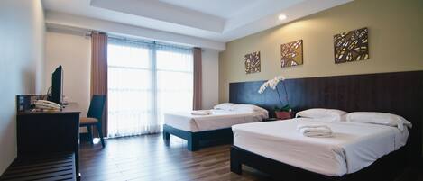 A hotel room with two beds, a desk with a telephone, a chair, and a ceiling fan.