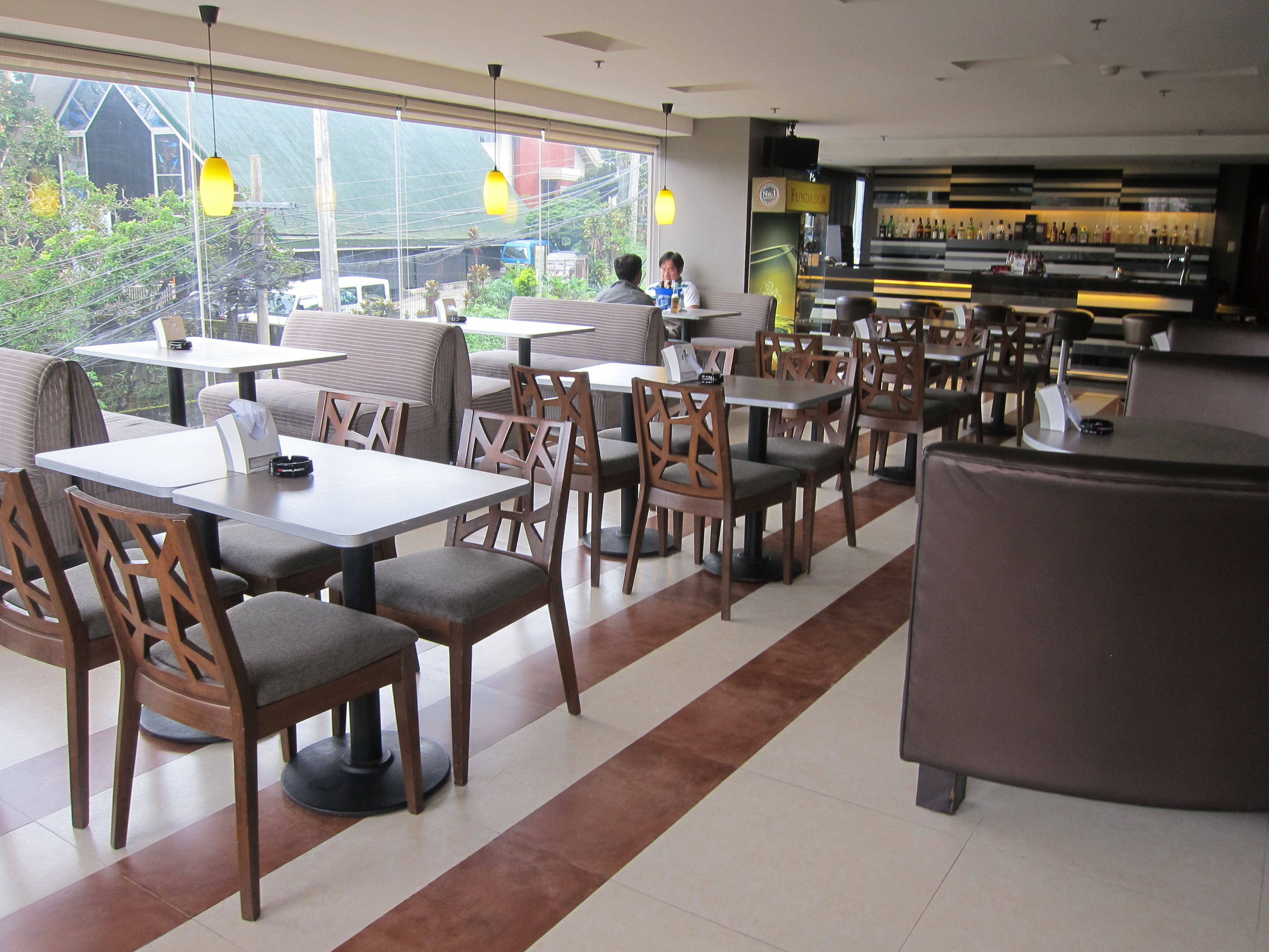 Un restaurant avec des banquettes et des tables, un bar et une vue sur l’extérieur.