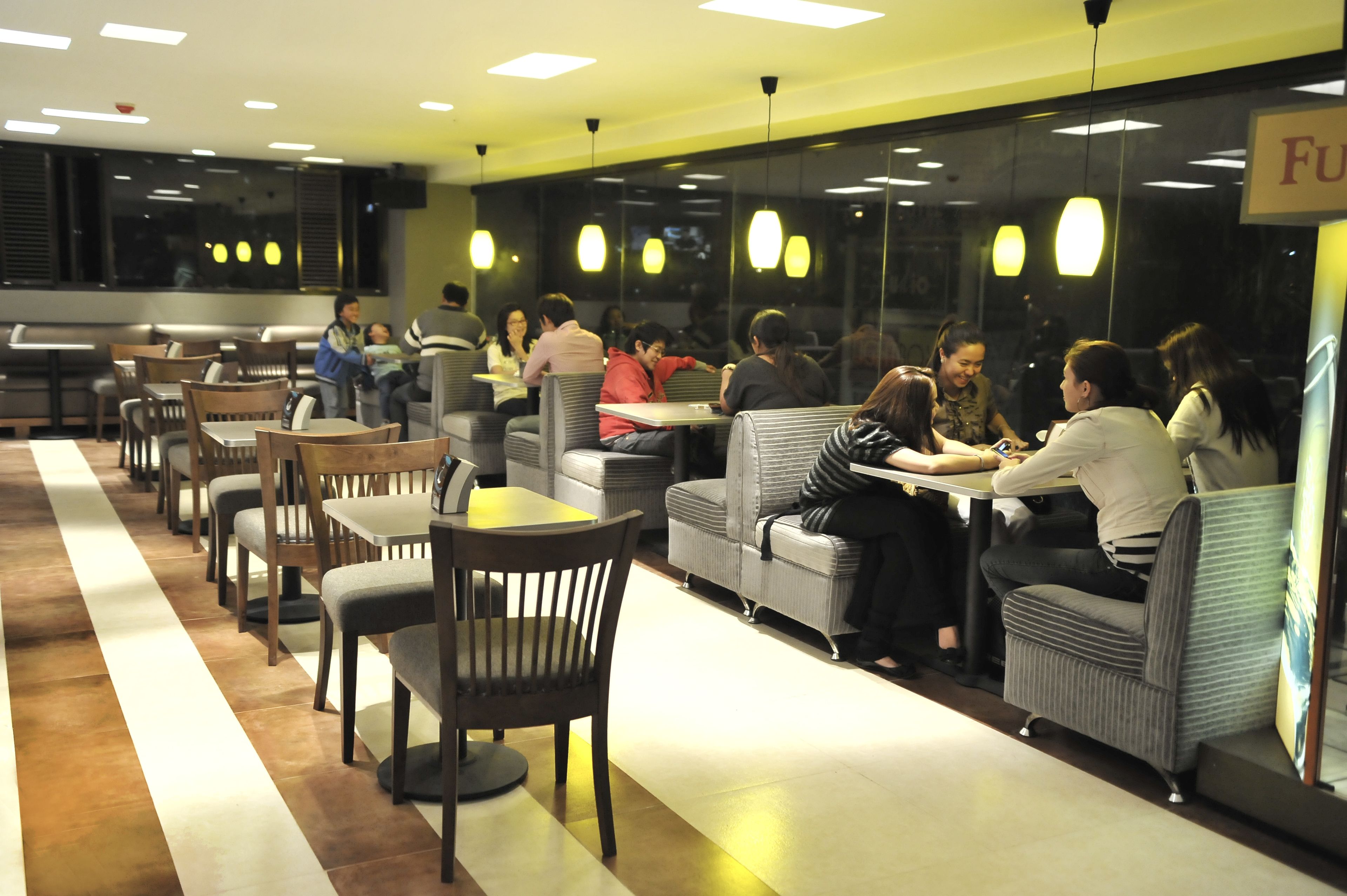Un restaurante con varias zonas de estar, incluidas cabinas y mesas, y una barra a lo largo de la pared de fondo.