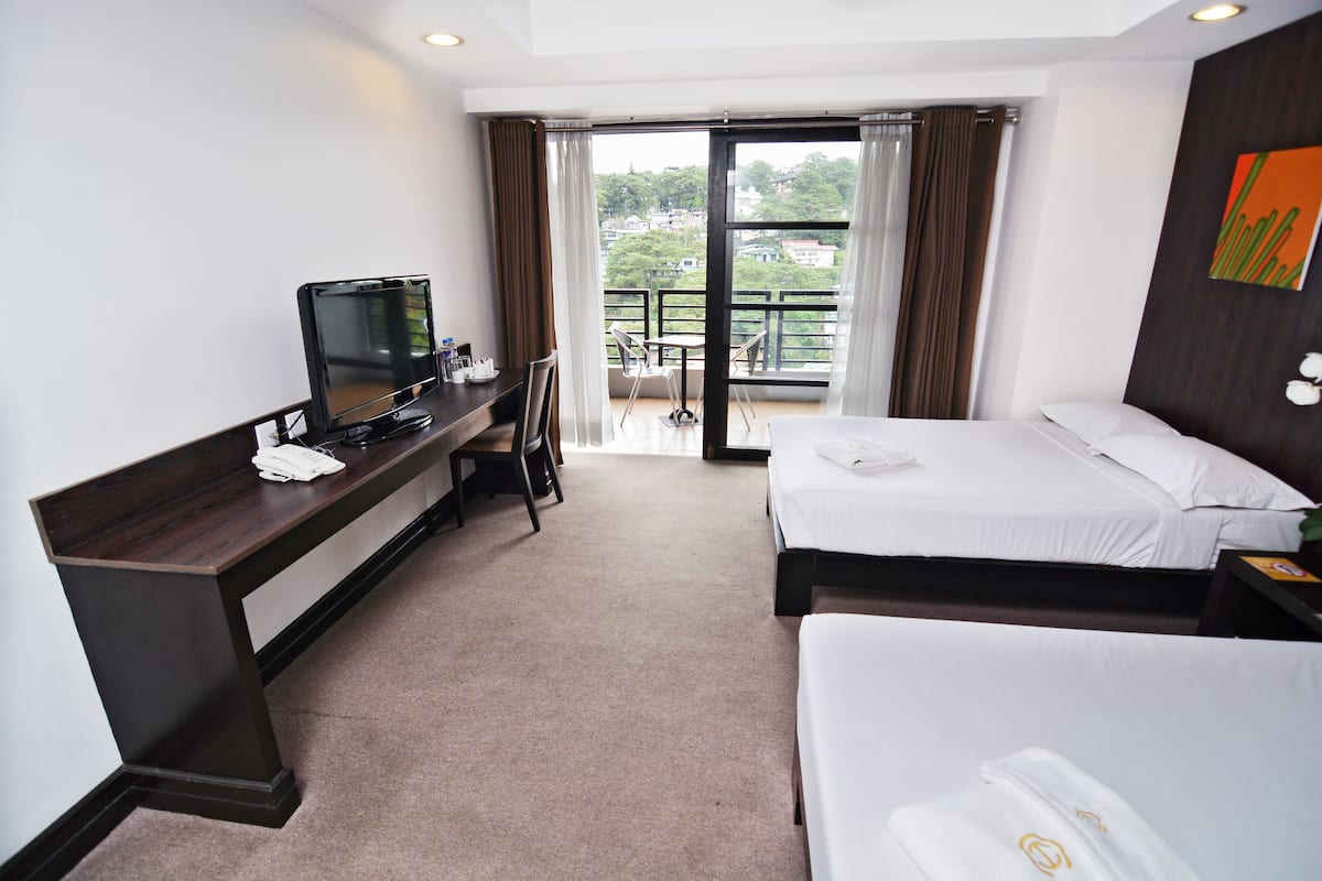 A hotel room with a bed, a desk with a computer, and a view of the outdoors.