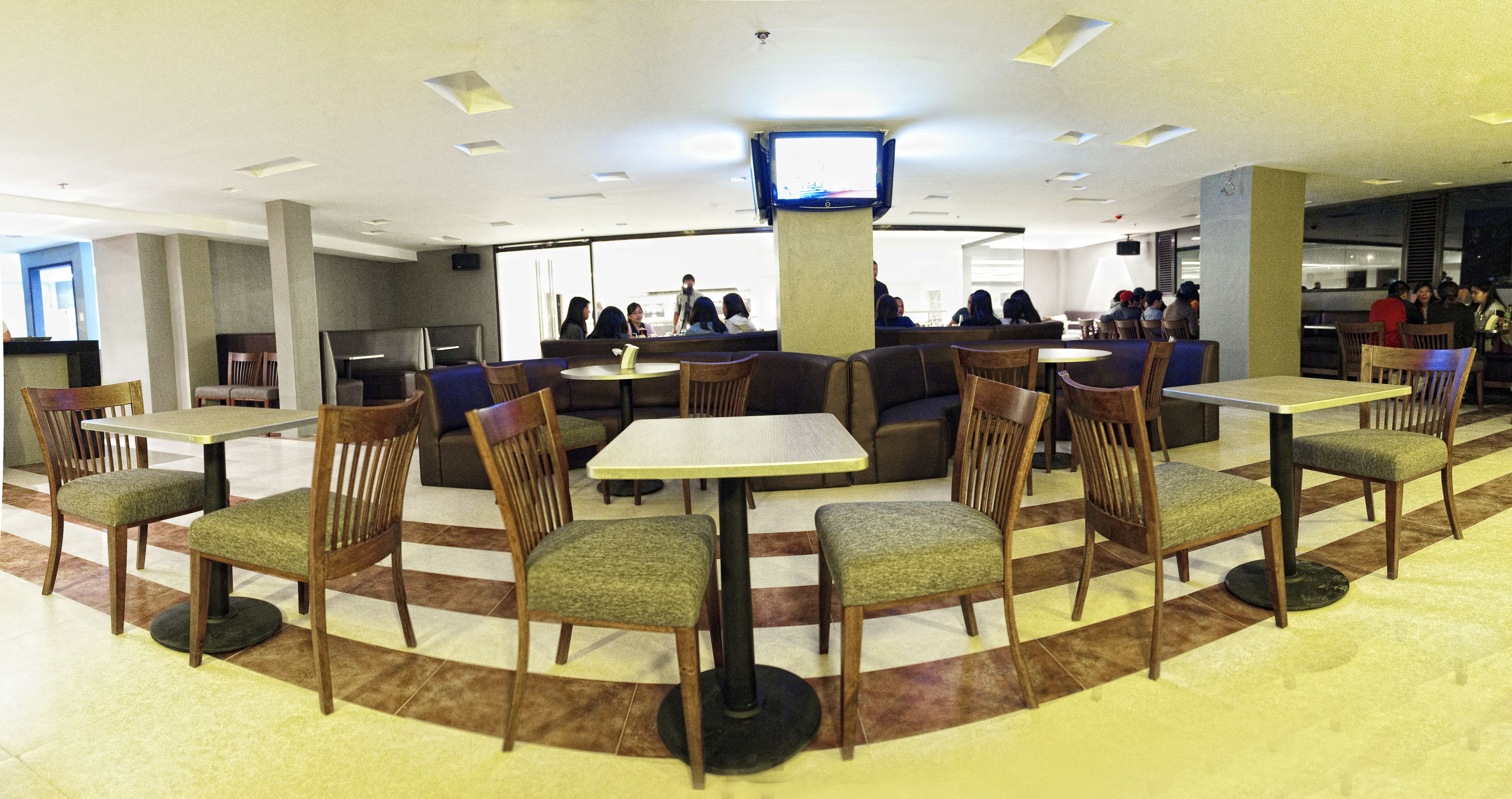 A restaurant with booths and tables, a flat-screen TV mounted on the wall, and a tiled floor.