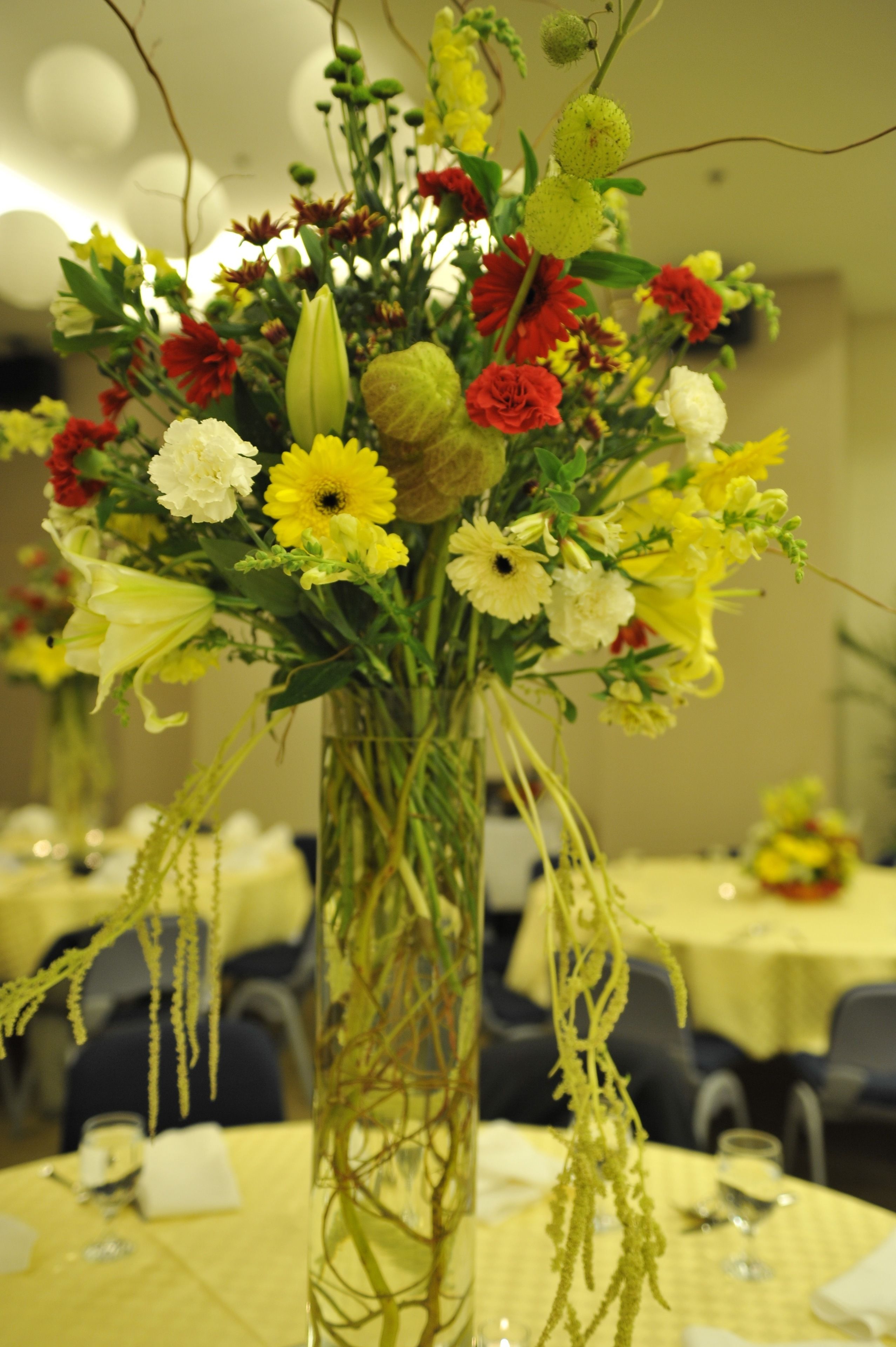 A table with a tall vase of flowers.
