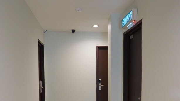 A hallway with a sign reading "KEYUARS" on the wall, a door on the right, and a door on the left. - My Inn (Bintulu)