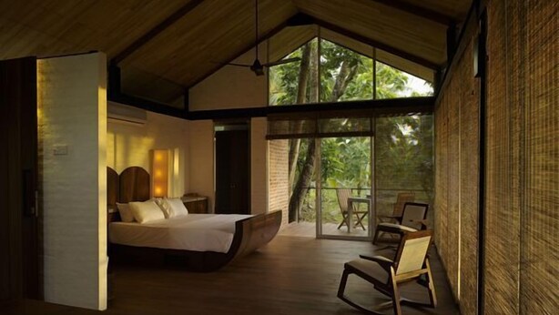 Un dormitorio moderno con una cama grande, un escritorio de madera y un balcón con sillas.